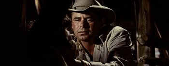 Movie still from “Jubal” (1956), directed by Delmer Daves – A man wearing a cowboy hat looking at the camera; Close Up shot, Over the shoulder angle