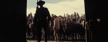 Movie still from “Jubal” (1956), directed by Delmer Daves – A crowd of men standing around a man holding a gun; Wide shot, Low angle