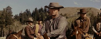 Movie still from “Jubal” (1956), directed by Delmer Daves – A man in a cowboy hat holding a rifle; Medium shot, Low angle