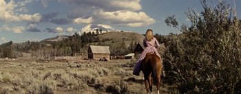 Movie still from “Jubal” (1956), directed by Delmer Daves – A woman in a pink dress riding on a horse; Wide shot, Low angle