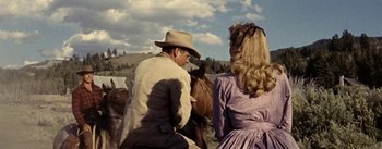 Movie still from “Jubal” (1956), directed by Delmer Daves – A man and a woman riding on the back of a brown horse; Medium shot, Over the shoulder angle