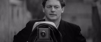 Movie still from “Jude” (1996), directed by Michael Winterbottom – A black - and - white photo of a man taking a picture; Close Up shot, Low angle