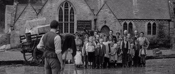 Movie still from “Jude” (1996), directed by Michael Winterbottom – A group of people standing in front of a building; Wide shot, Low angle