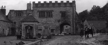 Movie still from “Jude” (1996), directed by Michael Winterbottom – An old stone building with a large stone arch; Extreme Wide shot, Low angle