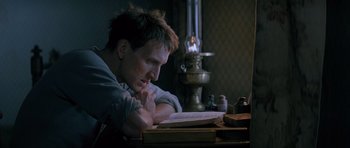 Movie still from “Jude” (1996), directed by Michael Winterbottom – A man sitting at a table reading a book; Close Up shot, High angle