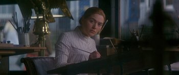 Movie still from “Jude” (1996), directed by Michael Winterbottom – A woman sitting at a table in front of a laptop; Medium shot, Over the shoulder angle