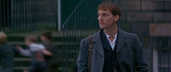 Movie still from “Jude” (1996), directed by Michael Winterbottom – A man in a suit and tie with a bag; Close Up shot, Over the shoulder angle