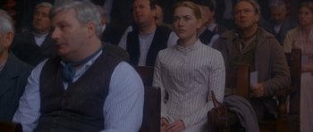 Movie still from “Jude” (1996), directed by Michael Winterbottom – A woman in a striped dress is sitting next to a man; Medium shot, Over the shoulder angle