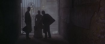 Movie still from “Jude” (1996), directed by Michael Winterbottom – A man and a woman standing in front of a gate; Wide shot, Over the shoulder angle