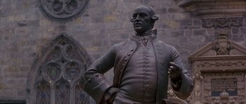 Movie still from “Jude” (1996), directed by Michael Winterbottom – A statue of a man in a suit; Medium shot, Low angle