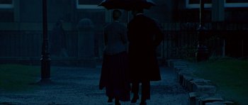 Movie still from “Jude” (1996), directed by Michael Winterbottom – A man and a woman standing under an umbrella in the dark; Wide shot, High angle