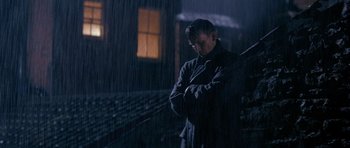 Movie still from “Jude” (1996), directed by Michael Winterbottom – A man standing in the rain with his arms crossed; Medium shot, Low angle
