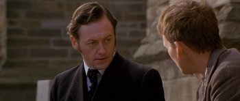 Movie still from “Jude” (1996), directed by Michael Winterbottom – A man wearing a suit and tie talking to another man; Close Up shot, Over the shoulder angle