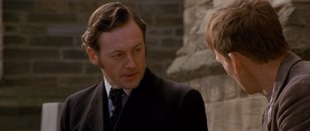 Movie still from “Jude” (1996), directed by Michael Winterbottom – A man wearing a suit and tie talking to another man; Close Up shot, Over the shoulder angle