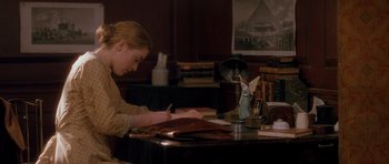 Movie still from “Jude” (1996), directed by Michael Winterbottom – A woman sitting at a desk writing on a piece of paper; Medium shot, High angle