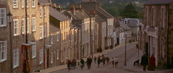 A group of people walking down a street near a row of houses