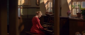 Movie still from “Jude” (1996), directed by Michael Winterbottom – A woman in a red dress is playing a piano; Medium shot, High angle