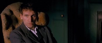 Movie still from “Jude” (1996), directed by Michael Winterbottom – A man sitting in a chair in a dark room; Close Up shot, Low angle