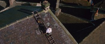 Movie still from “Jude” (1996), directed by Michael Winterbottom – A man standing on top of a ladder on a roof; Extreme Wide shot, Overhead angle