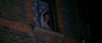 Movie still from “Jude” (1996), directed by Michael Winterbottom – A woman looking out of an open window at night; Medium shot, Low angle