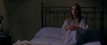 Movie still from “Jude” (1996), directed by Michael Winterbottom – A woman sitting on a bed in a room; Medium shot, High angle