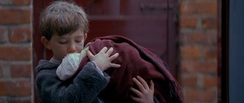 Movie still from “Jude” (1996), directed by Michael Winterbottom – A young boy is holding a blanket over his face; Close Up shot, Over the shoulder angle