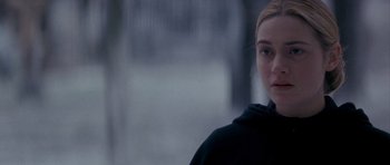 Movie still from “Jude” (1996), directed by Michael Winterbottom – A woman in a black hoodie standing in front of trees; Close Up shot, Over the shoulder angle