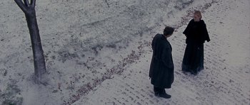 Movie still from “Jude” (1996), directed by Michael Winterbottom – A person standing on a snowy street looking at something; Extreme Wide shot, High angle