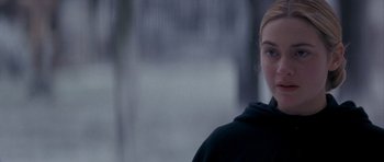 Movie still from “Jude” (1996), directed by Michael Winterbottom – A woman in a black hoodie standing in front of trees; Close Up shot, Over the shoulder angle