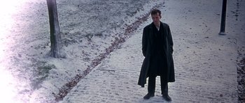 Movie still from “Jude” (1996), directed by Michael Winterbottom – A man standing on the side of a snow covered road; Wide shot, High angle