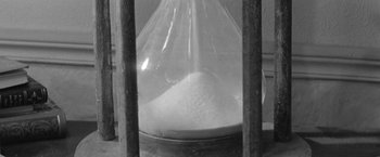 Movie still from “Jules and Jim” (1962), directed by François Truffaut – A glass bottle filled with white substance inside a wooden cage; Extreme Close Up shot, High angle