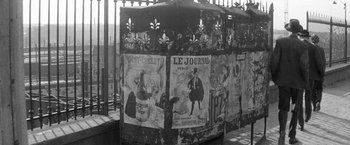 Movie still from “Jules and Jim” (1962), directed by François Truffaut – An old newspaper stand covered in advertisements; Wide shot, Low angle