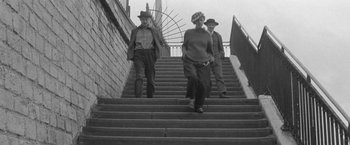 Movie still from “Jules and Jim” (1962), directed by François Truffaut – A group of people walking up some stairs; Wide shot, Low angle