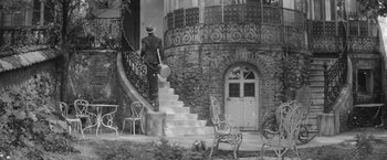 Movie still from “Jules and Jim” (1962), directed by François Truffaut – An old photo of a woman walking up the stairs; Wide shot, Low angle