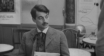 Movie still from “Jules and Jim” (1962), directed by François Truffaut – A black and white photo of a man wearing a suit and tie; Close Up shot, Over the shoulder angle