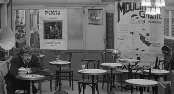 Movie still from “Jules and Jim” (1962), directed by François Truffaut – A black and white photo of tables and chairs in a restaurant; Wide shot, High angle
