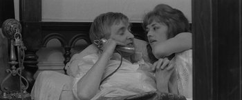 Movie still from “Jules and Jim” (1962), directed by François Truffaut – A man and a woman sitting on a bed talking on a phone; Close Up shot, High angle