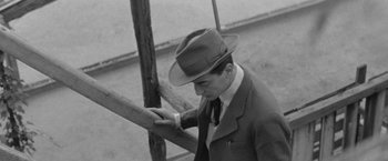 Movie still from “Jules and Jim” (1962), directed by François Truffaut – A black and white photo of a man in a suit and a hat; Medium shot, High angle