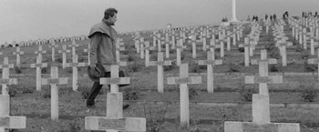 Movie still from “Jules and Jim” (1962), directed by François Truffaut – A man walking in front of a field of crosses; Wide shot, High angle