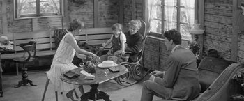 Movie still from “Jules and Jim” (1962), directed by François Truffaut – An old black and white photo of a family sitting at a table; Wide shot, High angle