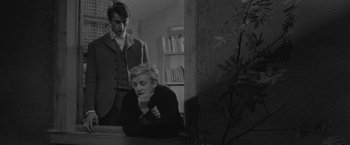 Movie still from “Jules and Jim” (1962), directed by François Truffaut – A man standing next to another man sitting at a table; Medium shot, Over the shoulder angle