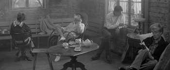 Movie still from “Jules and Jim” (1962), directed by François Truffaut – A man smoking a cigarette while sitting on a chair; Medium shot, High angle