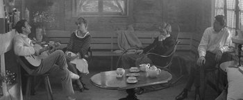 Movie still from “Jules and Jim” (1962), directed by François Truffaut – Two people sitting on a bench in front of a coffee table; Wide shot, High angle