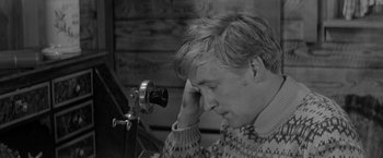 Movie still from “Jules and Jim” (1962), directed by François Truffaut – A man in a sweater looking at an old camera; Close Up shot, High angle