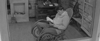 Movie still from “Jules and Jim” (1962), directed by François Truffaut – A man sitting in a rocking chair while reading a book; Medium shot, High angle