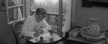 Movie still from “Jules and Jim” (1962), directed by François Truffaut – An older woman writing on a piece of paper; Medium shot, High angle