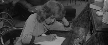 Movie still from “Jules and Jim” (1962), directed by François Truffaut – A woman writing on a piece of paper at a table; Close Up shot, High angle