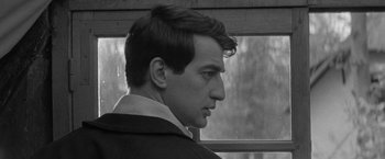 Movie still from “Jules and Jim” (1962), directed by François Truffaut – A black - and - white photo of a man looking out a window; Close Up shot, Low angle