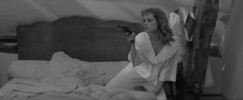 Movie still from “Jules and Jim” (1962), directed by François Truffaut – A black and white photo of a woman holding a gun; Medium shot, High angle