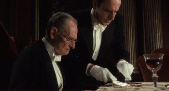 Movie still from “Julia” (1977), directed by Fred Zinnemann – Two men in tuxedos and white gloves cutting a cake; Medium shot, High angle